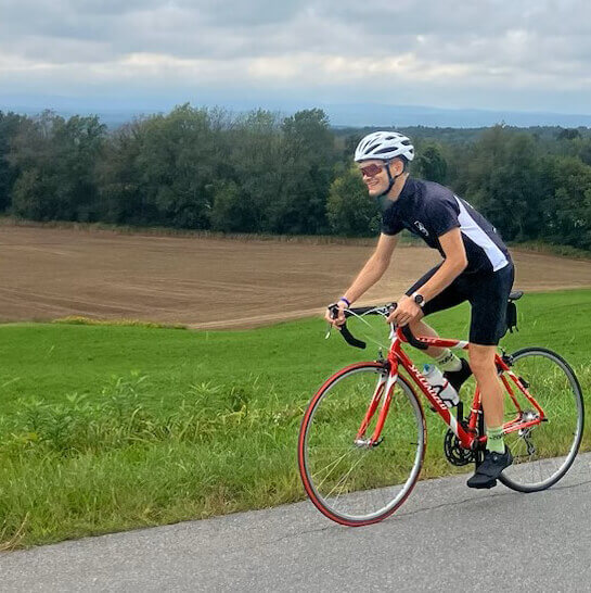 Guy riding his road bike near an open farm field